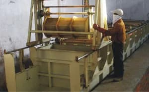 Zinc plating: an operator in a face mask at a plating barrel above the tanks of the plating line.