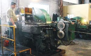 Bolt master: a bolt-making machine fed with steel wire, with its operator beside it.